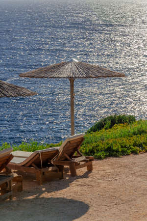 Straw beach umbrellas and sunbeds on the west coast of Zakynthos island in Greeceの写真素材
