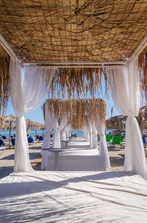 Straw beach umbrellas and sun chairs on a sandy beach on the east coast of Zakynthos island in Greeceの写真素材