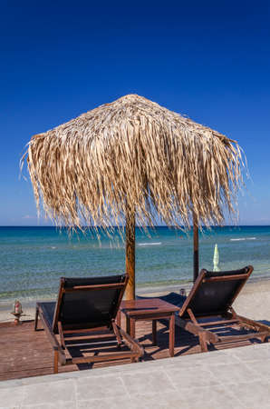 Straw beach umbrellas and sun chairs on a sandy beach on the east coast of Zakynthos island in Greeceの写真素材