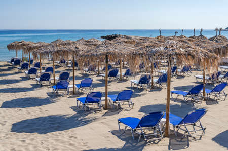 Straw beach umbrellas and sun chairs on a sandy beach on the east coast of Zakynthos island in Greeceの写真素材