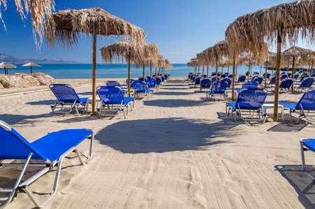 Straw beach umbrellas and sun chairs on a sandy beach on the east coast of Zakynthos island in Greeceの写真素材