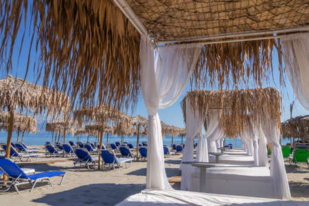 Straw beach umbrellas and sun chairs on a sandy beach on the east coast of Zakynthos island in Greeceの写真素材