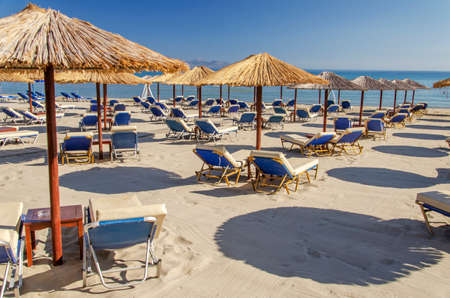 Straw beach umbrellas and sun chairs on a sandy beach on the east coast of Zakynthos island in Greeceの写真素材