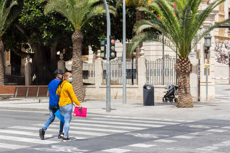 Alicante, Spain; June 30, 2020; A couple crossing the street at a zebra crossing with their face masks on a sunny day in Alicanteの写真素材