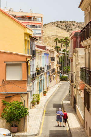 Alicante, Spain; July 08, 2020; street with colorful buildings with an old couple walking on a summer dayのeditorial素材