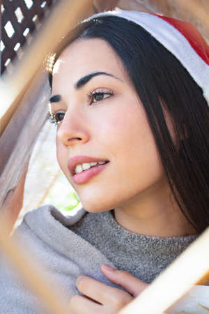 A shallow focus of a beautiful woman wearing a santa claus hat and a winter blanket