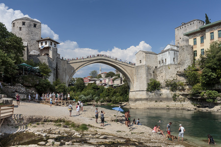 MOSTAR, BOSNIA AND HERZEGOVINA - AUGUST 05, 2015: Tourist and locals walking near Old bridge in Mostar and swimming in Neretva river. Included to the UNESCO heritageのeditorial素材