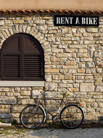 BALE, CROATIA - MAY 10, 2014: Old rusty bicycle parked under rent a bike sign in Bale, Croatiaのeditorial素材