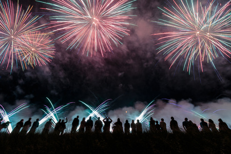 Group of people enjoying fireworks show in a carnival or holiday. People in silhouette.の写真素材