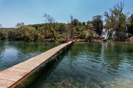 LJUBUSKI, BOSNIA AND HERZEGOVINA - JULY 12, 2016: Kravice waterfall in Bosnia and Herzegovina. People walking across the wooden bridge.のeditorial素材