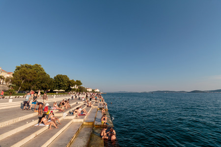 ZADAR, CROATIA - JULY 10, 2016: People relaxing and swimming at Zadar famoust Sea Organs. The sea organ won European Prize for Urban Public Space award in 2006. Copy spaceのeditorial素材