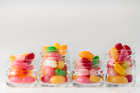 Jelly beans in small glass jars on white backgroundの写真素材