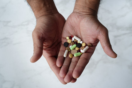 Men's hands of warm brown skin color hold pills and vitamin nutritional supplements. Healthcare.の写真素材
