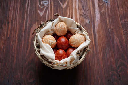 Easter eggs of beige and brown color with lace print lie in a basket on a wooden table.の写真素材