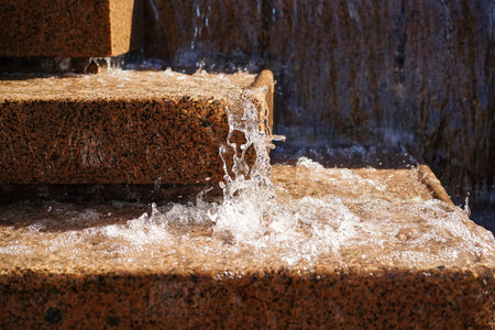 Close-up of the steps of a water fountain with splashing and cascading water in a city park.の写真素材