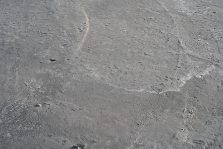 The gray background of drying hand-mixed concrete. Waves of lime from river sand and the silhouettes...