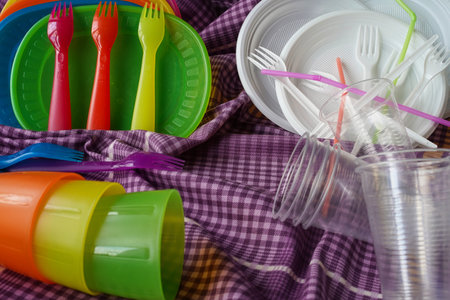 Reusable plastic picnic tableware versus disposable plastic tableware. Colorful and white plates,...