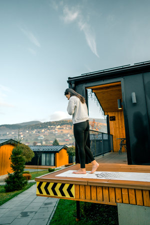 Young woman stands on nails on the terrace near the house early in the morning. Sadhu boards. Nail conceptの写真素材