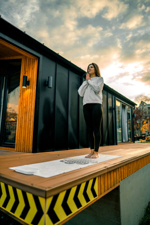 Young woman stands on nails on the terrace near the house early in the morning.の写真素材