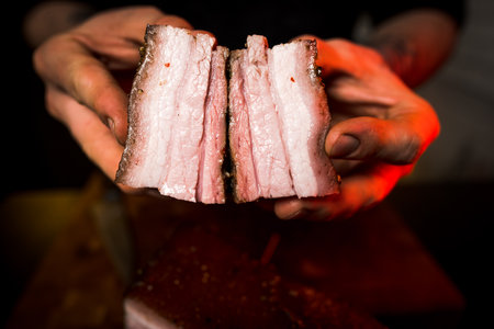 Sliced smoked meat in the hands of a professional butcher.の写真素材