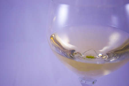 A glass of white wine on a purple backgroungの写真素材