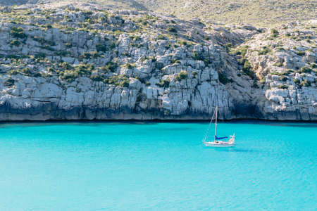Sailing boat on blue water beach mountain backgroundの写真素材