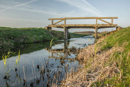 Concrete bridge over the Uherka River in Poland with a grassy bank. View on a sunny day