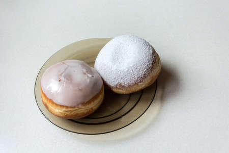 Donuts with icing and sugar powder on a glass plate - closeup