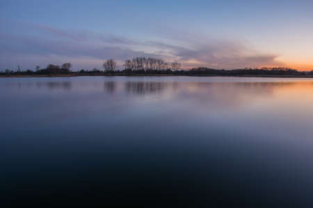 Calm lake and colorful clouds after sunset - evening view