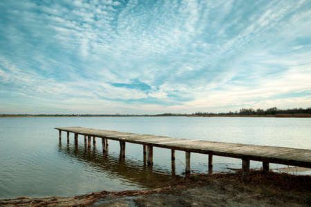 A long wooden bridge on the water and cloudscapeの写真素材