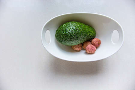 Green avocado and lychee in a white bowl on a white background, top viewの写真素材