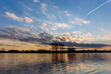 Sunset on the lake and trees on the horizon, evening view