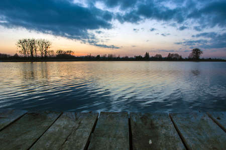 Clouds over the lake after sunset and a wooden bridge, evening viewの写真素材