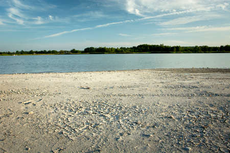 Dry river bank, trees on the horizon and blue sky