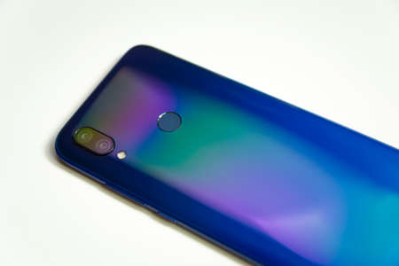 The back of a blue smartphone with two cameras and a flash, illuminated with colored light on a...