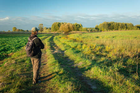 A man with a backpack standing on a dirt road, view in sunny dayの写真素材