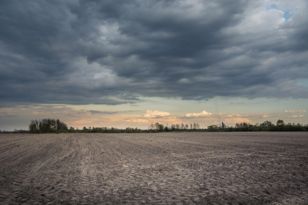 Plowed field, dark rainy clouds on the sky, spring rural viewの写真素材