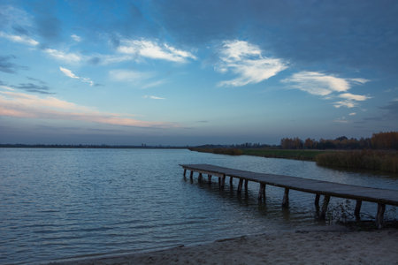 Lake shore with a wooden platform and evening sky, autumn viewの写真素材