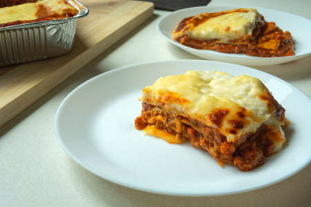 Baked pieces of lasagne on a white round plateの写真素材