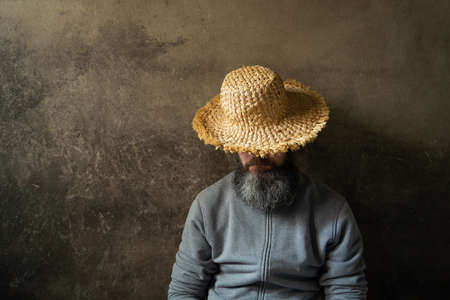 A napping man with a beard in a hat against the background of a dark wallの写真素材