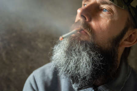 The man with the long beard is smoking a cigarette, portraitの写真素材