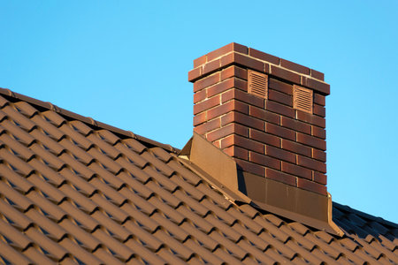 Brick chimney on the roof and clear blue skyの写真素材