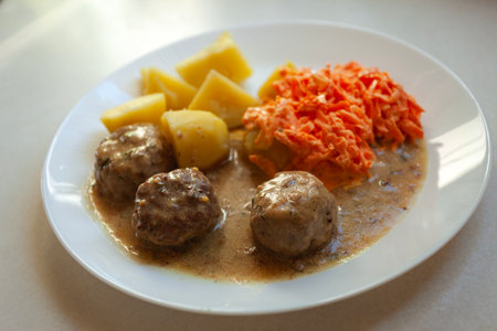 Meatballs with potatoes and carrot salad on a white plateの写真素材