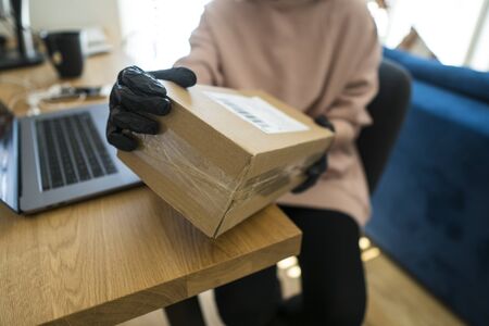 Young blonde girl in protective gloves holding cardboard boxes. Epidemic. Coronavirus. Covid-19....