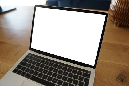 Young woman working on laptop. Laptop on wooden desk with white screen. Green plant in background. Mockup for web design. Close up.の写真素材