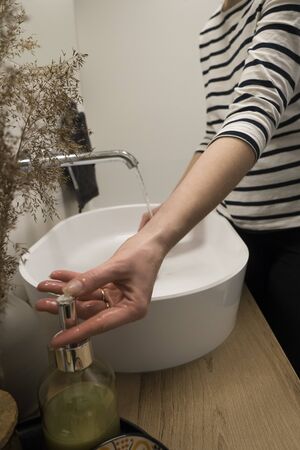 COVID-19 Coronavirus. Woman washing hands with foam soap and hot water at bathroom. Hygiene, preventing coronavirus. Corona Virus pandemic protection by cleaning hands frequently.の写真素材