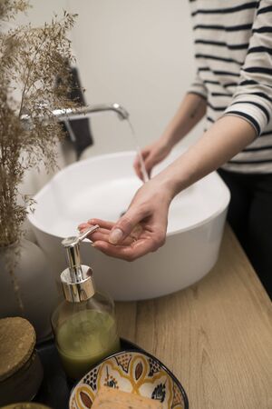 COVID-19 Coronavirus. Woman washing hands with foam soap and hot water at bathroom. Hygiene, preventing coronavirus. Corona Virus pandemic protection by cleaning hands frequently.の写真素材