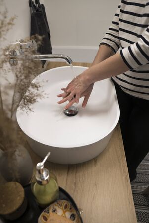 COVID-19 Coronavirus. Woman washing hands with foam soap and hot water at bathroom. Hygiene, preventing coronavirus. Corona Virus pandemic protection by cleaning hands frequently.の写真素材