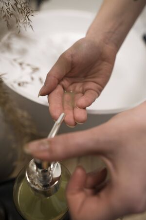 COVID-19 Coronavirus. Woman washing hands with foam soap and hot water at bathroom. Hygiene, preventing coronavirus. Corona Virus pandemic protection by cleaning hands frequently.の写真素材