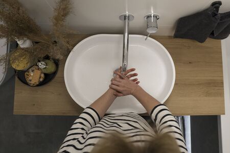 COVID-19 Coronavirus. Woman washing hands with foam soap and hot water at bathroom. Hygiene, preventing coronavirus. Corona Virus pandemic protection by cleaning hands frequently.の写真素材